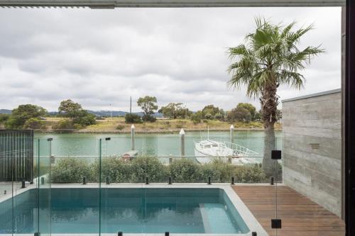 a swimming pool with a view of the water at Sunset Marina - An Architectural Gem by the Beach in Safety Beach
