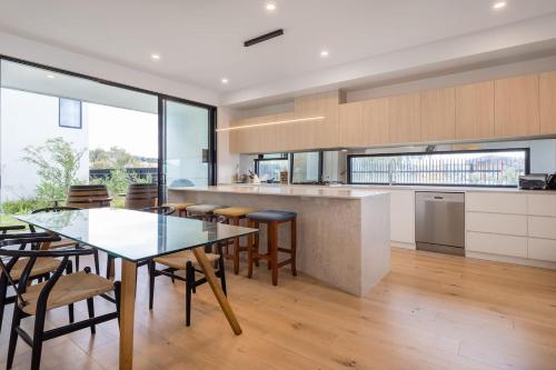 a kitchen with a table and chairs and a counter at Sunset Marina - An Architectural Gem by the Beach in Safety Beach