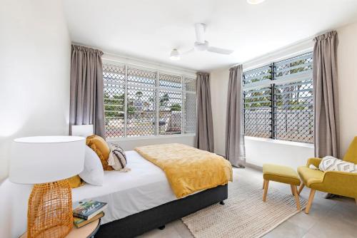 a bedroom with a bed and a chair and windows at Botanica Trio - Best Nightcliff Residence for Groups in Nightcliff