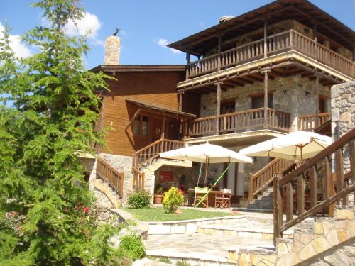 a large wooden house with umbrellas in the yard at Suites Efharis Filoxenon in Feneos