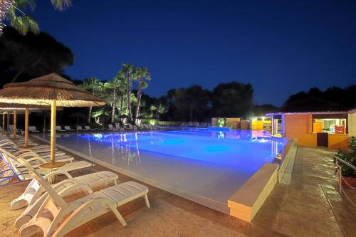 a large swimming pool with chairs and an umbrella at Hotel Solara in Conca Specchiulla