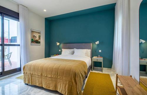 een slaapkamer met een groot bed met een blauwe muur bij Carmen de Triana in Sevilla