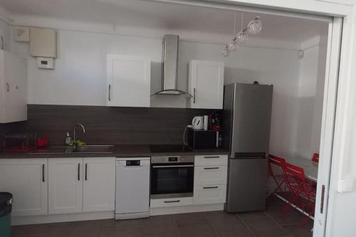 une cuisine avec des armoires blanches et un réfrigérateur en acier inoxydable dans l'établissement Barcarès village - RdC de maison indép. 2/6 p, au Barcarès