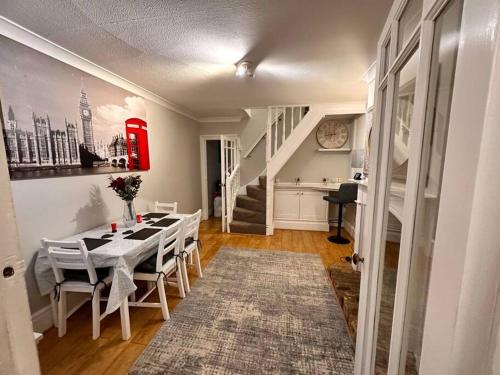 a dining room with a table and chairs and a staircase at Charming 2 Bedroom Cottage in Staines Upon Thames in Staines upon Thames