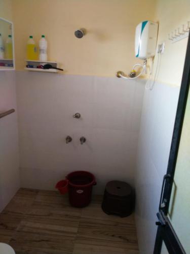 a bathroom with a bucket in the corner of a room at Patel's Home in Bhuj