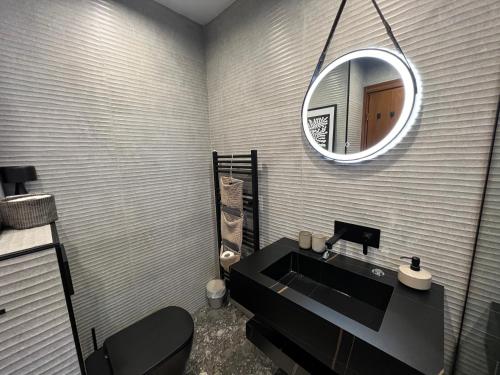 ein Bad mit einem schwarzen Waschbecken und einem Spiegel in der Unterkunft Katarino Spa Chalet in Raslog