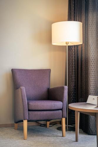 a purple chair and a lamp in a hotel room at The Lodge Sporthotel - Golfclub Eppan in Appiano sulla Strada del Vino