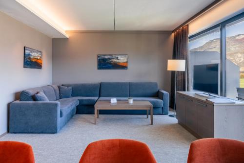 a living room with a blue couch and a tv at The Lodge Sporthotel - Golfclub Eppan in Appiano sulla Strada del Vino