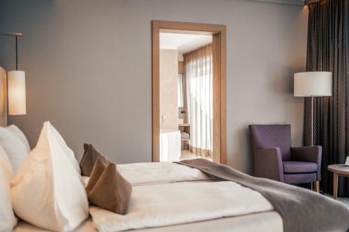 a hotel room with a bed and a chair at The Lodge Sporthotel - Golfclub Eppan in Appiano sulla Strada del Vino