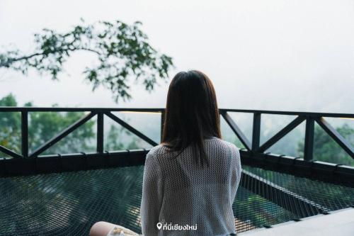 a woman sitting on a bench looking out of a window at Amaze Muang Khai in Ban Kai Noi