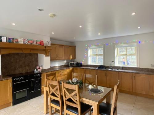 a kitchen with wooden cabinets and a table with chairs at Rostrevor Valley 6-Br Sleeps 20 w Hot Tub & View in Newry