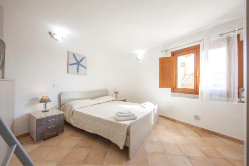 - une chambre blanche avec un lit et une fenêtre dans l'établissement Apartment I Nidi dei Cormorani, à Costa Rei