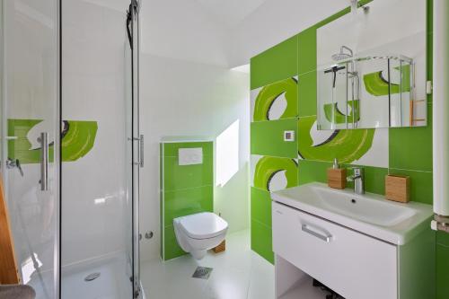 ein grün-weißes Bad mit einem WC und einer Dusche in der Unterkunft Villa Vin - Pool, ruhig, strandnah, Klimaanlage, Außenküche, Meeresnähe, Gästebetreuer in Babići