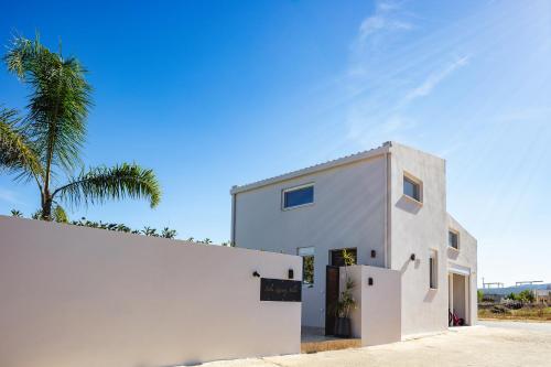 a white house with a palm tree behind it at Solis Villa, with Heated Pool & 5 minutes to Beach, By ThinkVilla in Kavros