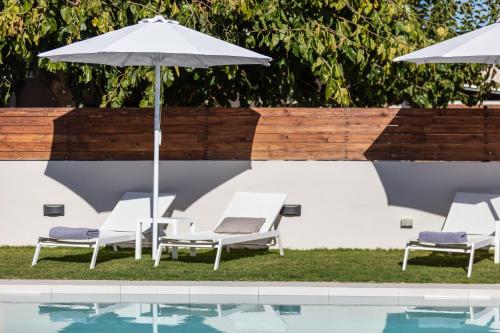 a group of chairs and an umbrella next to a pool at Solis Villa, with Heated Pool & 5 minutes to Beach, By ThinkVilla in Kavros