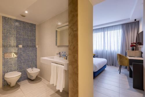 a bathroom with a sink and a toilet and a bed at Kenzi Solazur in Tangier