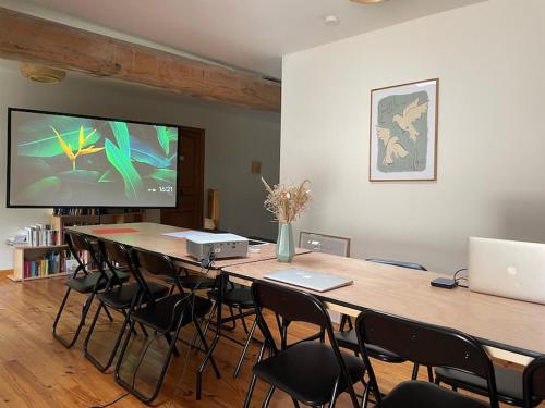 a conference room with a table with chairs and a television at L'ancien Relais de Poste*** in Saint-Dier-dʼAuvergne