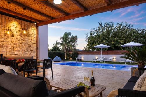 an outdoor patio with a pool and a table and chairs at Solis Villa, with Heated Pool & 5 minutes to Beach, By ThinkVilla in Kavros