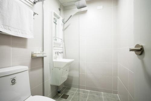 a white bathroom with a toilet and a shower at Parkavenue Guesthouse in Seoul