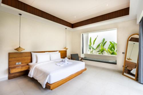 a bedroom with a large white bed and a window at J4 Villas Sanur in Sanur