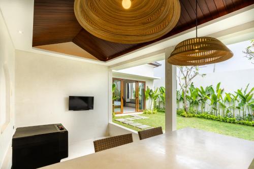 an open living room with a dining table and a television at J4 Villas Sanur in Sanur