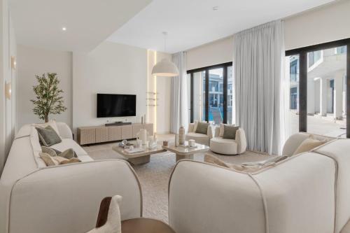 a living room with white furniture and a tv at Stunning Palm Villa with Rooftop Garden, Resort Style Pool and Beach by Exclusive Holiday Homes in Dubai