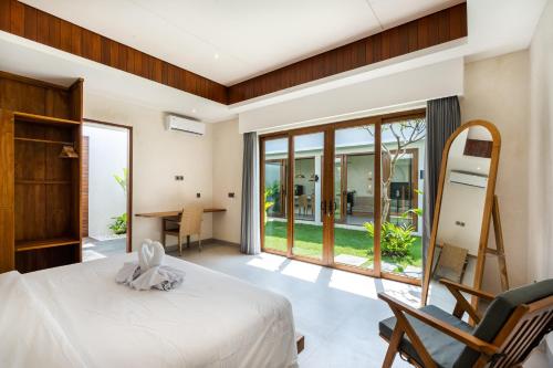 a bedroom with a bed and a desk and a window at J4 Villas Sanur in Sanur