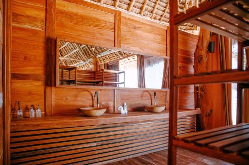 bagno con due lavandini in una camera in legno di TIKI Beach Club & Resort a Bwejuu