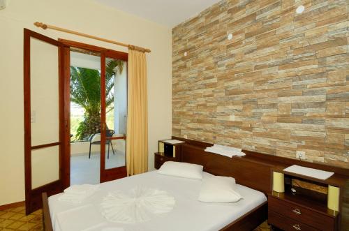 a bedroom with a bed and a brick wall at Zambia Apartments in Plakias