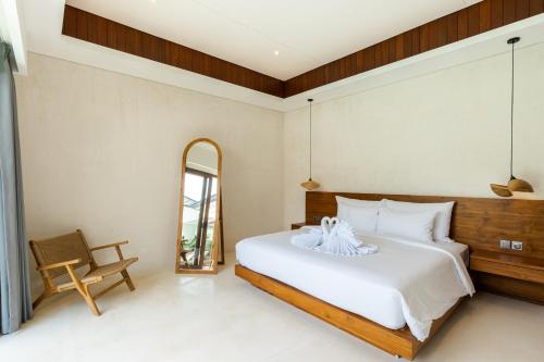 a bedroom with a large white bed and a mirror at J4 Villas Sanur in Sanur