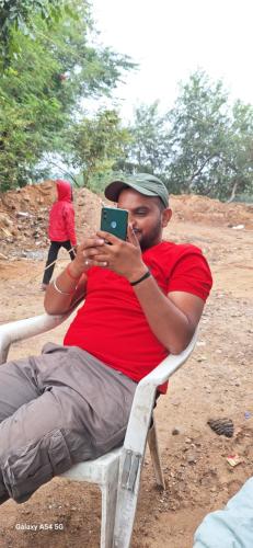 un hombre sentado en una silla tomando una foto con un celular en The Golden Palm Khajuraho, en Khajurāho