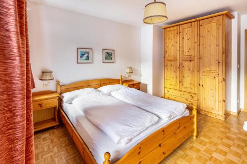a bedroom with a wooden bed and a wooden cabinet at Majon Garneté Buffaure 5 in Pozza di Fassa