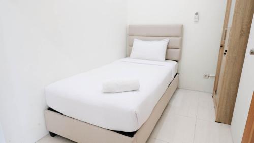 2BR Apartment at Puncak Bukit Golf Surabaya near Lenmarc Mall By Travelio في سورابايا: سرير أبيض صغير في غرفة بيضاء