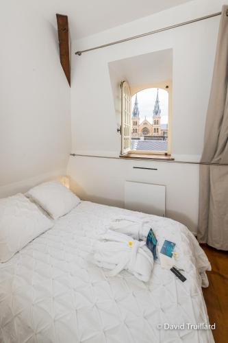 - un lit blanc avec des serviettes et une fenêtre dans l'établissement Suites Mana - Te Fiti en Plein Centre de la Place Ducale avec vue sur les toits, à Charleville-Mézières