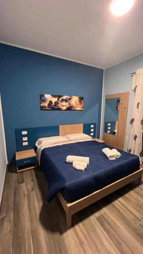 a blue bedroom with a bed with towels on it at ALMA B&B Cosenza CENTRO in Cosenza