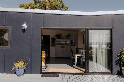 a black house with a sliding glass door at The Sandy Sister in Dodges Ferry