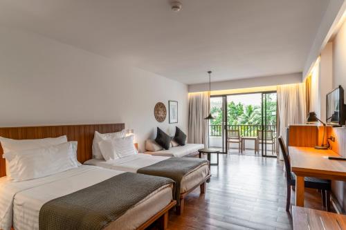 a hotel room with two beds and a desk at Sunprime Kamala Beach in Kamala Beach