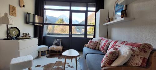 Una sala de estar con un sofá azul y una ventana. en Vue exceptionnelle T2 Saint Lary soulan, 4 personnes, en Saint-Lary-Soulan