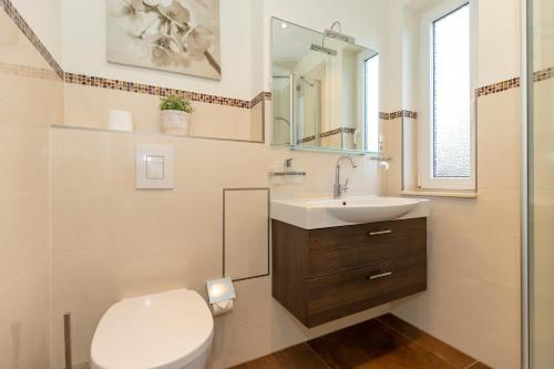ein Badezimmer mit einem WC, einem Waschbecken und einem Spiegel in der Unterkunft Yachthafenresidenz in Kühlungsborn