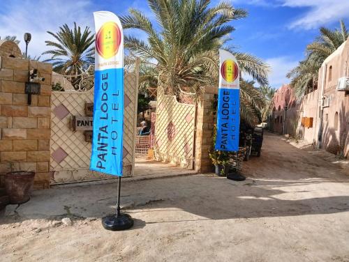 two blue and white signs in front of a building at Panta Lodge Siwa بنتا لودج سيوة in Siwa
