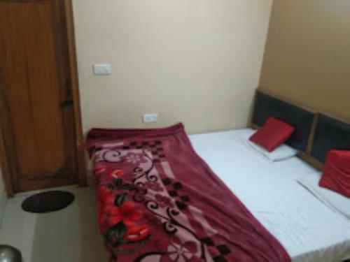 a bed with a red blanket on it in a room at Hotel Balaji , Gwalior in Gwalior