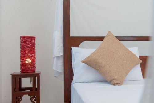 a bed with a pillow and a lamp on a table at The Manor House by Sansi in Zanzibar City