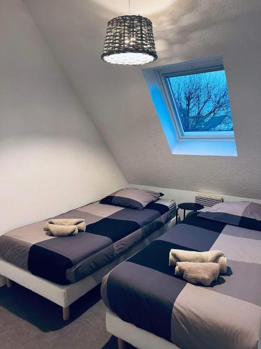 une chambre avec trois lits et une fenêtre dans l'établissement Cottage Opale, à Stella-Plage