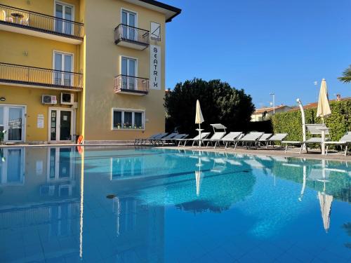 uma piscina em frente a um hotel com mesas e cadeiras em Bardolino City Life Apartments em Bardolino