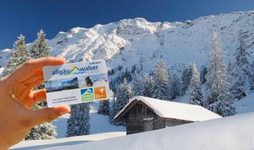 a person holding up a ski vacation ticket in front of a cabin at Casa Enrico in Oberjoch