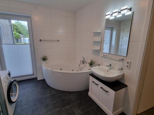 La grande salle de bains blanche est pourvue d'une baignoire et d'un lavabo. dans l'établissement Park-Apartment Scharmützelsee Wohnung 1, à Wendisch Rietz