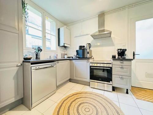 uma cozinha com electrodomésticos brancos e um tapete no chão em Maison des chenizelles em Laon