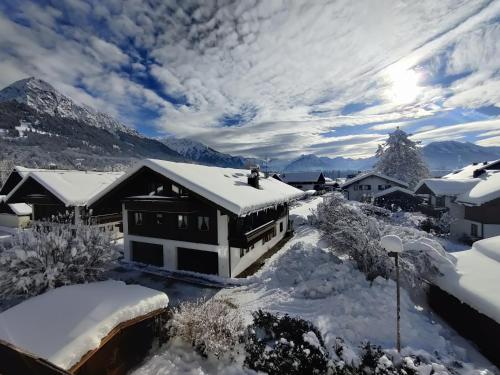 a house covered in snow with mountains in the background at Schittlerhof in Fischen