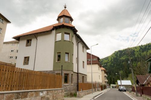 un bâtiment avec une tour sur le côté d'une rue dans l'établissement Pensiunea Violin Panzió, à Băile Tuşnad