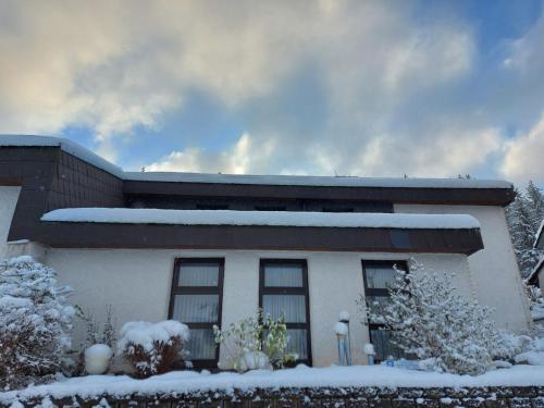 a house with snow on the front of it at Gästehaus Hochrhönblick in Schönau an der Brend